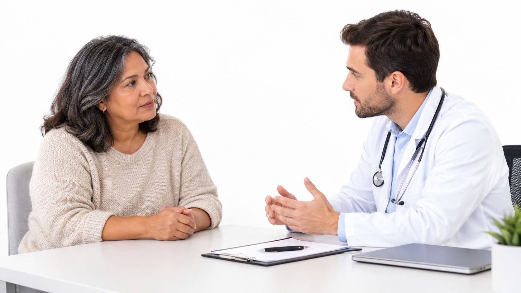A female patient sitting at a desk and listening to a male doctor during a consultation.
