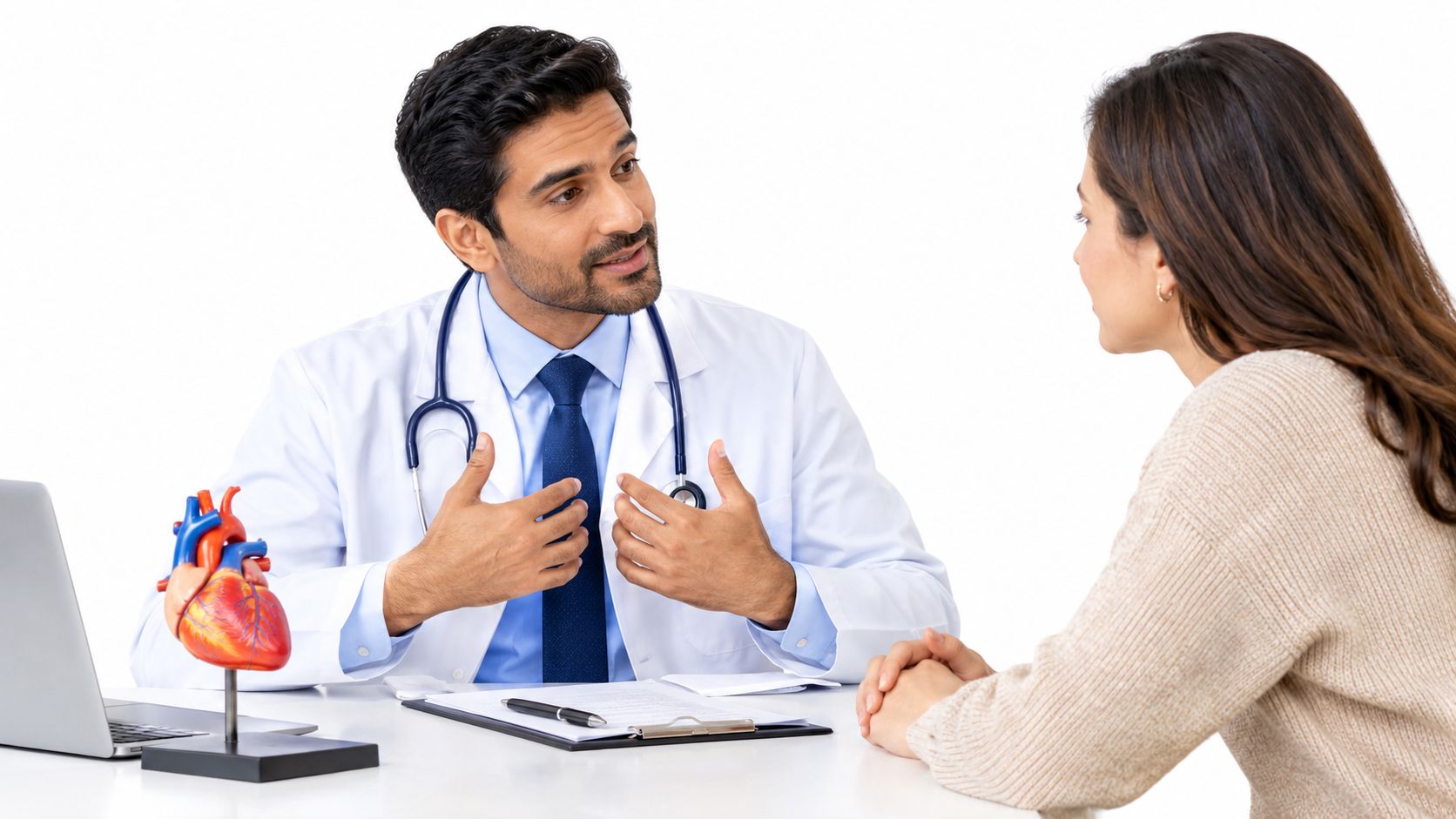 A doctor in a lab coat talking to a female patient about heart health using an anatomical model.